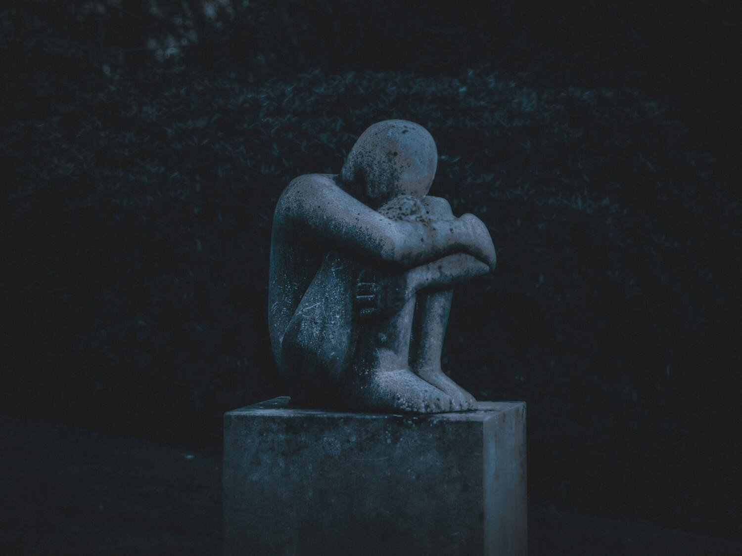 statue of person hugging knees while sitting down