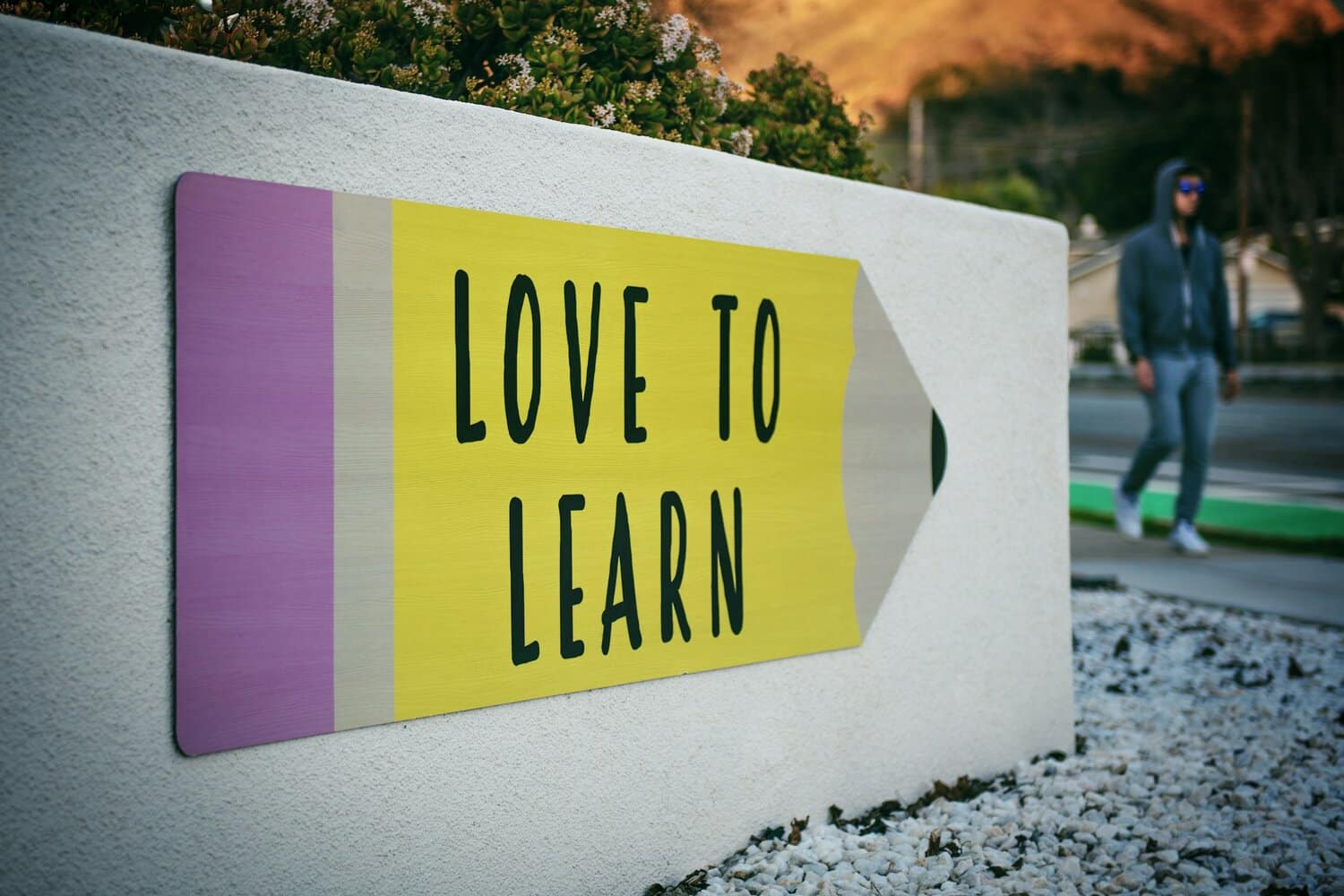 sign with a pencil that says love to learn - in purple and yellow