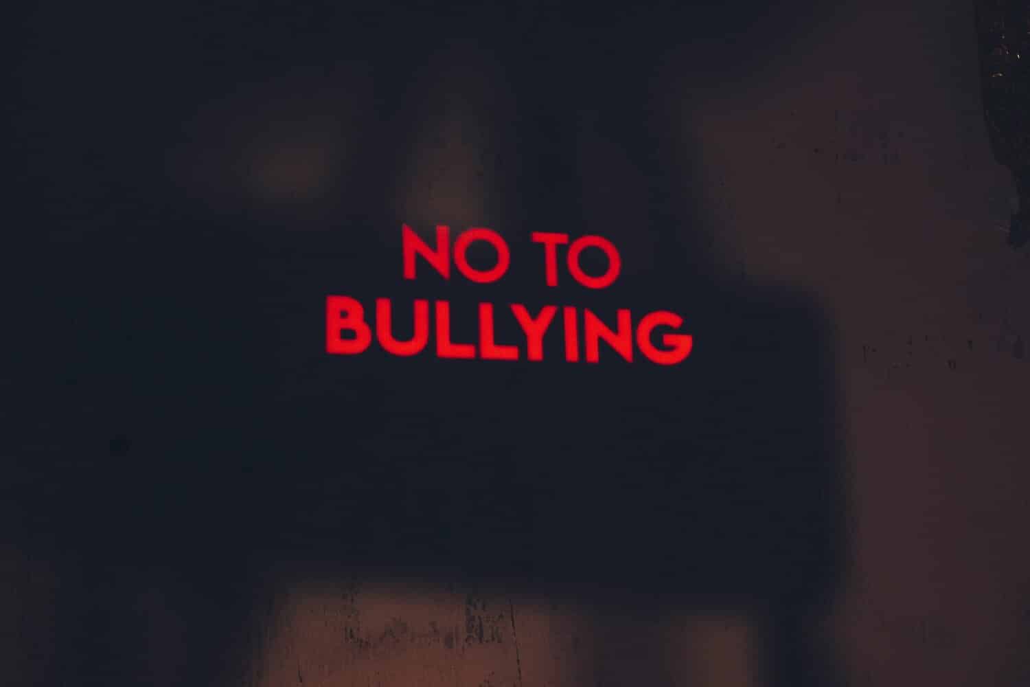black background with red neon sign that says no to bullying
