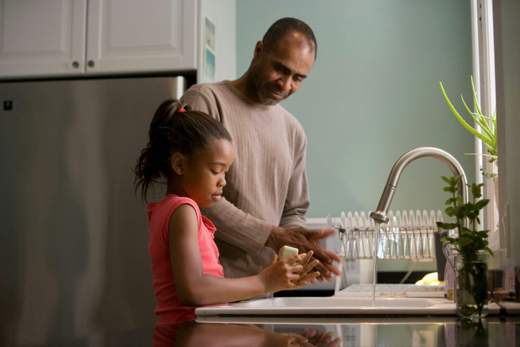 dad and young daughter working in kitchen together near sink