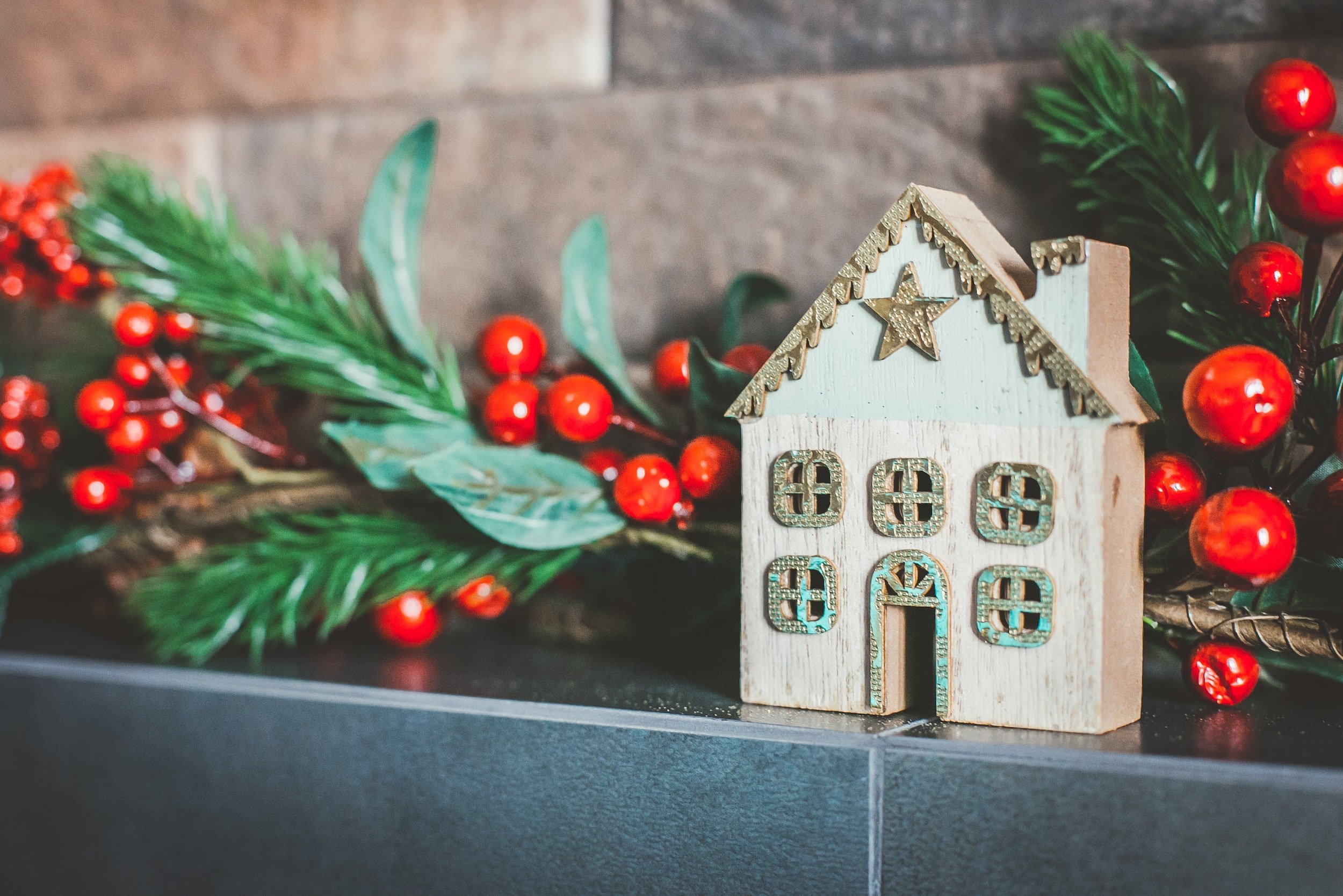 gingerbread house on mantle with red holiday berries and green leaves