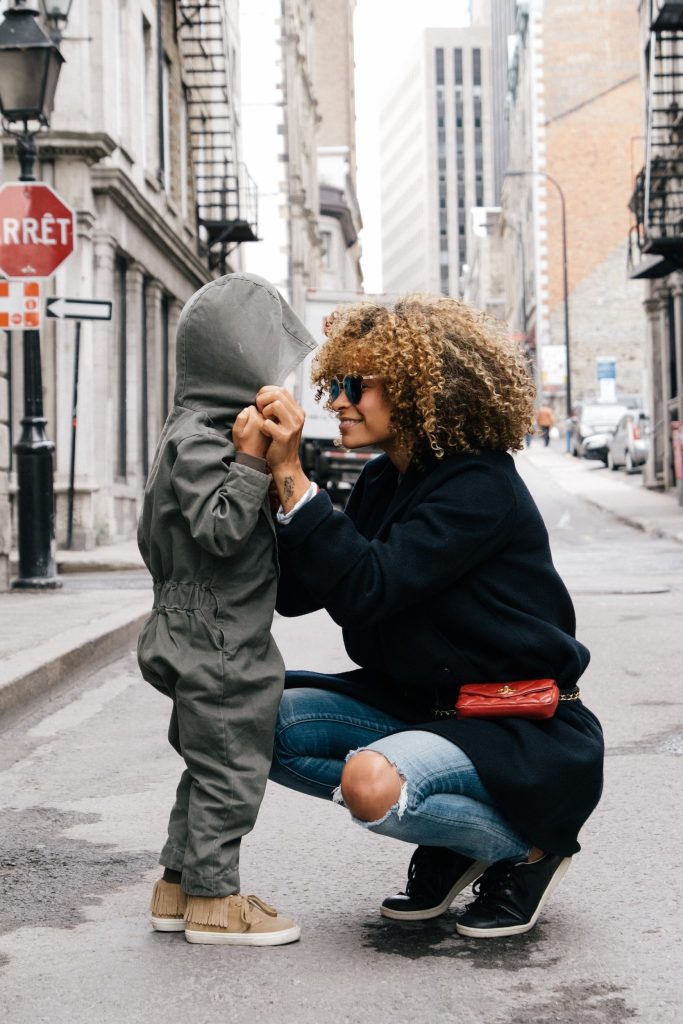 mother kneeling on city street talking face-to-face with her child