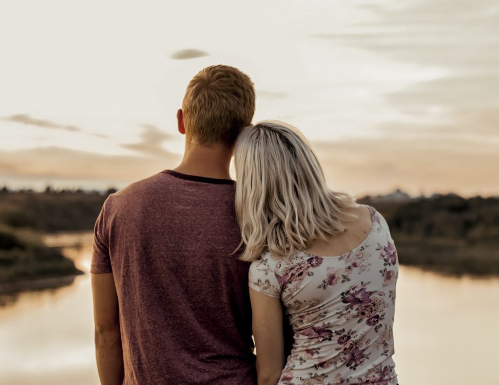 boyfriend and girlfriend cuddling in front of river