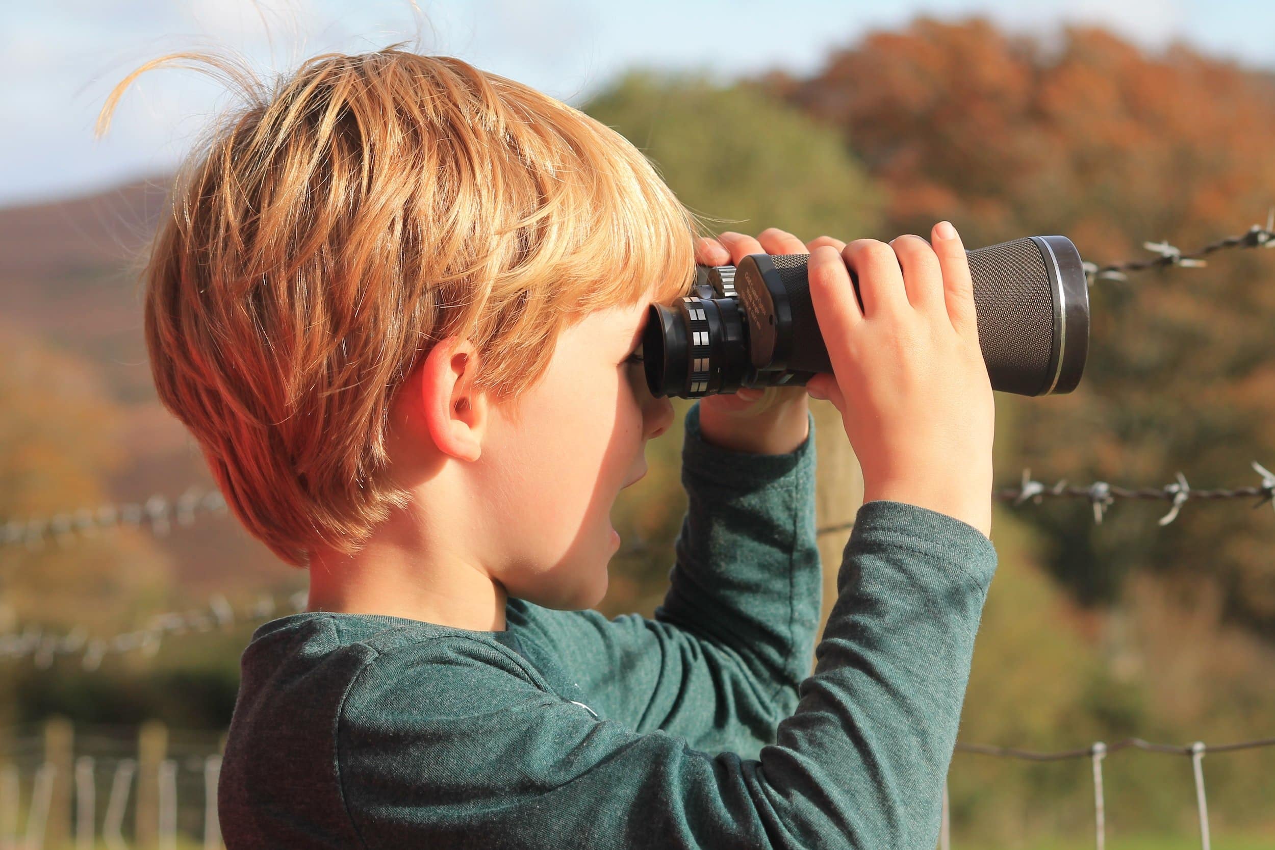 little boy looking through binoculars