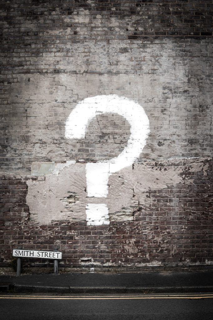 question mark painted on gray brick wall