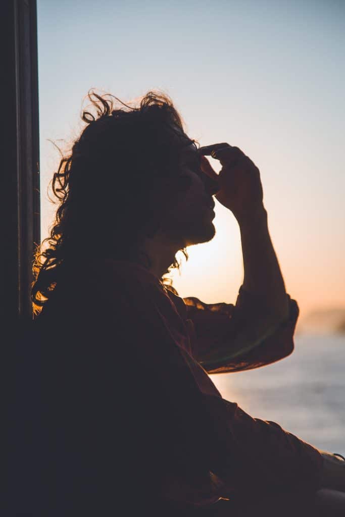 outline of woman holding hand to face with ocean and sky in background