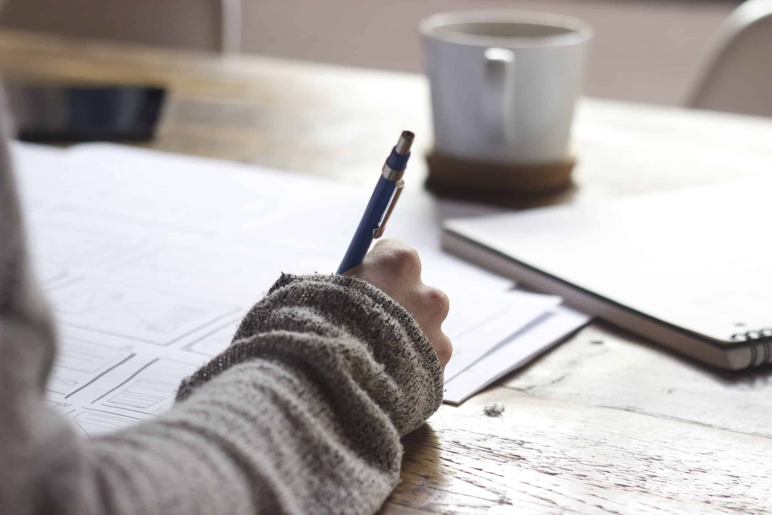 woman holding pen, writing on paper