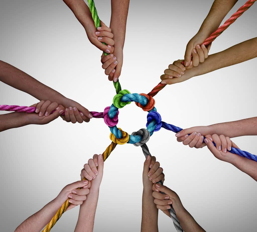 six people holding multi-colored rope in a circle